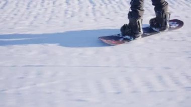 Karlı arazide ilerleyen snowboardcuların bir izleme görüntüsü.