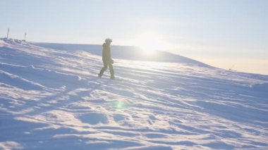 Çocukların parlak güneşin arka planına doğru karları oyup yol alırken çekilen bir görüntüsü.