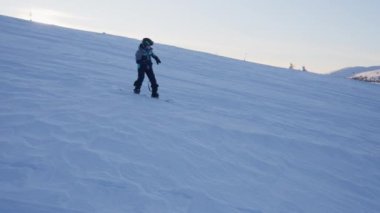 Bir iz sürme çekimi, snowboard yapan ve heyecan verici atlayışlar yapan bir çocuğu yakalıyor.