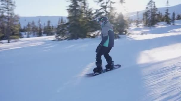 昼間のスノーボード上の斜面の挑戦を取る若い男の子の追跡ショット 動画クリップ