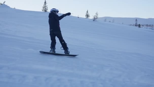 雪に覆われた地形を恐れずに征服する若いスノーボーダーの追跡ショット ストック映像