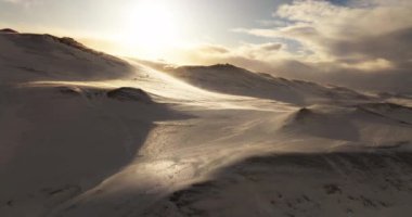 Gün batımındaki meltemi yakalayan bir dron zarif bir şekilde karla kaplı dağları süpürüyor