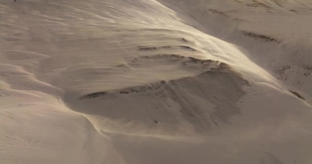 日没に雪山の風景を一掃する強力な風を捉えたドローン ストック動画