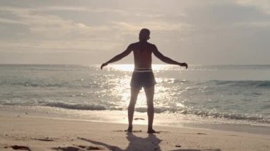 Bir Muay Thai boksörü çarpışan deniz dalgalarına karşı ağır çekimde antrenman yapar.