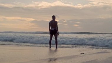 Güçlü deniz dalgalarına karşı ayakta duran bir Muay Thai boksörü