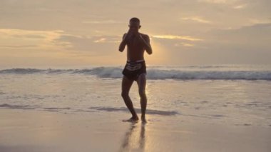 Bir Muay Thai boksörü güneşin batışına güçlü yumruklar ve tekmeler atar.