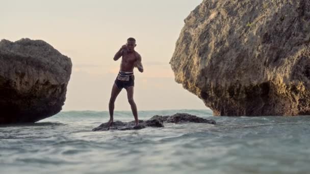 ムエタイのボクサーは海のダイナミックな背景の中で彼のスキルを磨きます ストック映像