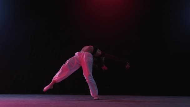 赤いスタジオの照明と黒い背景の中で優雅に踊る女性 ロイヤリティフリーストック映像