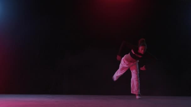 一位年轻女子在浓烟中闪烁着迷人的红光下舞姿 营造出迷人的气氛 — 图库视频影像