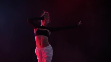 Bir kızın büyüleyici dansı, duman içindeki kırmızı stüdyo ışıklarının büyüleyici parıltısıyla aydınlanıyor.