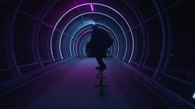 Bir BMX sürücüsü etkileyici ayakta numaralar sergiliyor gece bir yaya köprüsü boyunca düzgünce yuvarlanırken