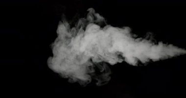 Duman bulutları siyah bir zemin boyunca yayılarak soyut şekiller ve desenler oluşturarak havaya yayılıyor ve yavaşça dağılıyor.