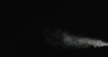 Siyah arka planda esen yoğun duman izlerinin yavaş çekim görüntüsü. Işıklandırma, havaya yayılan dumanın şeklini ve hareketini vurgular.