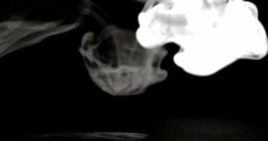 Bir duman akıntısı karanlık bir arka plana doğru iniyor. Duman yüzeye doğru akar ve yüzeye dağılmadan önce daha yoğun ve daha tanımlı hale gelir.