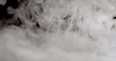 Bir duman akıntısı düz bir yüzeye düşer ve yayılır. Duman kalın ve dalgalı görünüyor, ayrıntılı girdap ve desenlerle. Işıklandırma dumanın şeklini ve dokusunu vurguluyor.