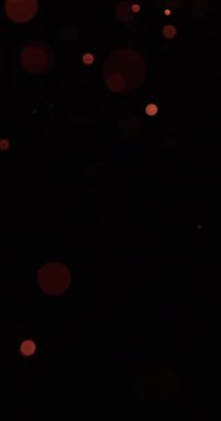 Karanlık bir arka plana çarpıcı bir bokeh etkisi ile zarifçe yüzen ruhani kum parçacıkları