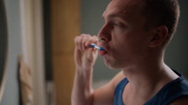Bir adamın dişlerini titizlikle fırçalarken ki yan görüntüsü.