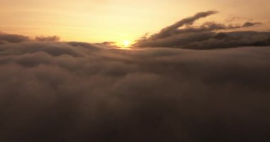Çarpıcı bir hava manzarası bulutlar denizinin üstündeki günbatımının dinginliğini yakalar.