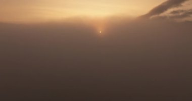 Güneş, bulutlardan oluşan bir battaniyenin üzerine sıcak bir parıltı saçıyor, gökyüzünü altın renginde boyuyor.