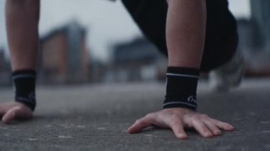 Yakın çekim, bir adamın kollarının ve bacaklarının dinamik hareketini dış yüzeyde koşarken yakalar. Adam bileklik takıyor.