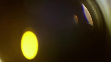 İki belirgin ışık küreli bir mercek parlıyor. Arka plan koyu kahverengi tonlar ve sol üst köşesinde sarı bir eğim var.