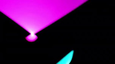 Canlı neon, pembe ve cyan ışıklar enerjik bir şekilde dans ediyor. Karanlık bir arkaplanda.