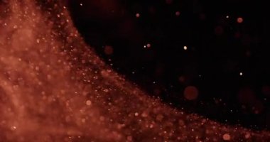 Titreyen kum tanecikleri koyu bir zemin üzerinde bokeh daireler çizerek yüzerler.