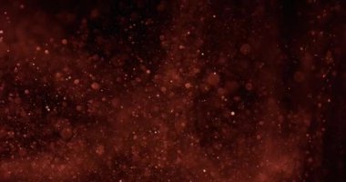 Büyüleyici kahverengi parçacıklar yavaş çekimde karanlık bir arkaplana doğru sürükleniyor