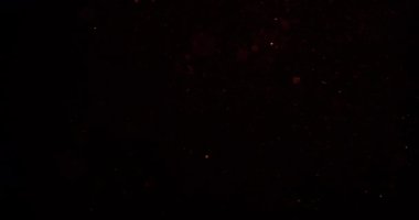 Parlayan kum parçacıkları ve bokeh etkileri yavaşça karanlık bir arkaplana inerek büyüleyici bir ışık ve hareket görüntüsü oluşturur.