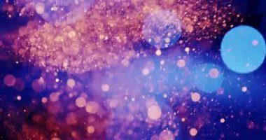 Çok sayıda küçük, odaksız ışık parçacıkları koyu bir arkaplanda yüzerler. Parçacıklar ağırlıklı olarak altın, turuncu, mavi ve pembe renklerin karışımından oluşan sıcak tonludur.