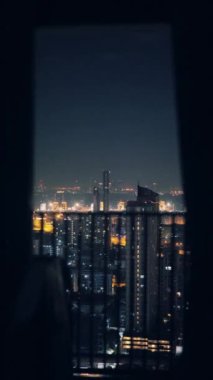 Gece vakti balkondan çekilen göz kamaştırıcı şehir manzarası. Parlak şehir ışıkları sergileniyor.