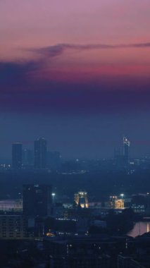 Modern şehir manzarası alacakaranlıkta pürüzsüz bir şekilde kaybolan gün ışığına karşı kentsel ışıkların dingin güzelliğini yakalıyor.