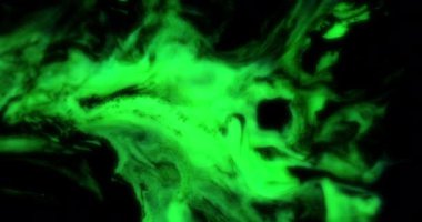 Neon yeşil sıvı siyah bir arkaplanda yavaşça yayılır.