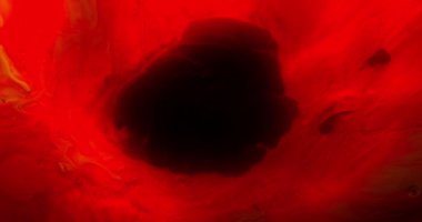 Canlı kırmızı pigment dinamik olarak siyah bir tuval üzerinde döner ve merkezde büyüleyici dairesel bir desen oluşturur.