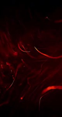 Enerjik kırmızı atomlar, karanlık bir zemin üzerinde hızla dönerler, enerji ve hareket yayarlar.