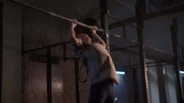 Bir kadın barfiks çekerek hızını kullanarak çenesini barın üstüne kaldırıyor.