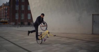 Yelek ve kravat takan yetenekli bir sürücü BMX 'in baş aşağı manüel numaralarını ustalıkla gösterir.