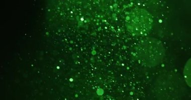 Yeşil renkli parçacıklar karanlık bir arkaplanda uçarak mistik ve parıltılı bir etki yaratırlar.