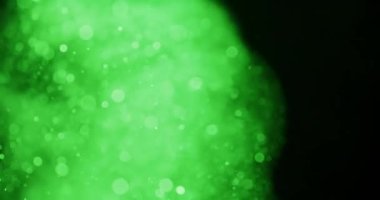 Cennetsel yeşil parçacıklar zarifçe karanlığın içinde sürükleniyor, dingin ve gizemli bir ortam yaratıyor.