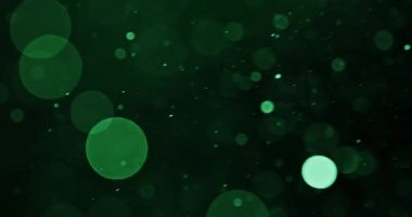 Canlı yeşil bokeh parçacıkları ekran boyunca çapraz akarak büyüleyici bir görsel zemin oluşturur.
