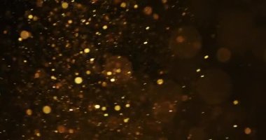 Sarı renkli parçacıklar karanlıkta yukarı doğru dairesel bir şekilde hareket ederler.