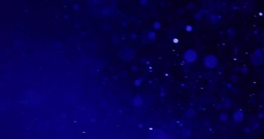 Narin mavi parçacıkların yumuşak bokeh daireler arasında yavaşça sola süzülüp huzur verici ve büyüleyici bir görsel ortam yarattıkları sakin bir sahne.