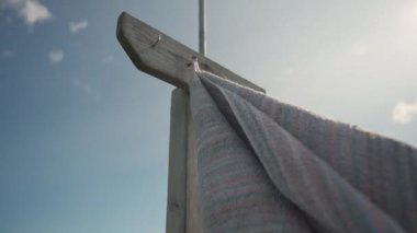 Tahta bir direkte bir havlu sallanıyor, rüzgarla hareket ediyor, gökyüzüne karşı.
