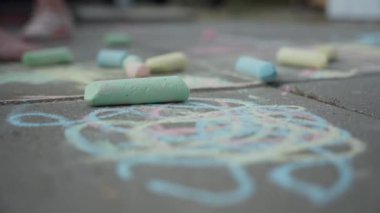 Renkli tebeşir karalamalarıyla beton kaldırım, canlı ve yaratıcı sanat eserleri sergileniyor.
