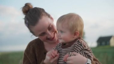 Bir kadın neşeyle bebeğinin kollarını açar ve kapatır, şefkatli ve neşeli bir etkileşim anını paylaşır