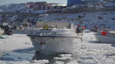 Buzlu bir limana demirlemiş, karla kaplı rıhtımlar ve donmuş sularla çevrili, mevsimin dinginliğini yansıtan, pitoresk bir kış manzarası.