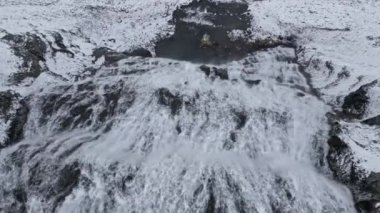 Dynjandi Şelalesi 'nin hava perspektifi göz kamaştırıcı karlı bir arazide akıyor, görkemli akışı ve sakin kış manzarasını vurguluyor.