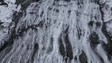 Dynjandi şelalesinin karlı uçurumlar arasında akan güçlü akıntısını gösteren bir çekim.