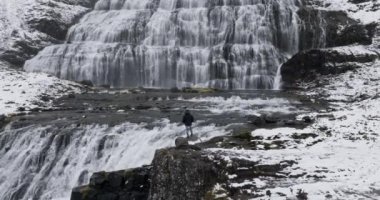 Bir maceraperest uçurumun kenarında dikilip Dynjandi Şelalesi 'ne bakarak engebeli uçurum kenarındaki ihtişamı yakalıyor.