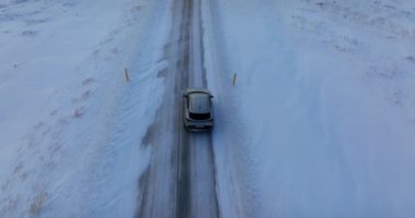 Karlı arazide gezinen bir arabanın insansız hava aracı görüntüsü. Kış manzarası boyunca yolculuğunu gösteriyor.